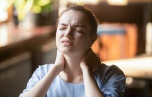 Tired young woman feel neck pain rubbing stiff neck