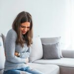 Woman having painful stomachache on bed