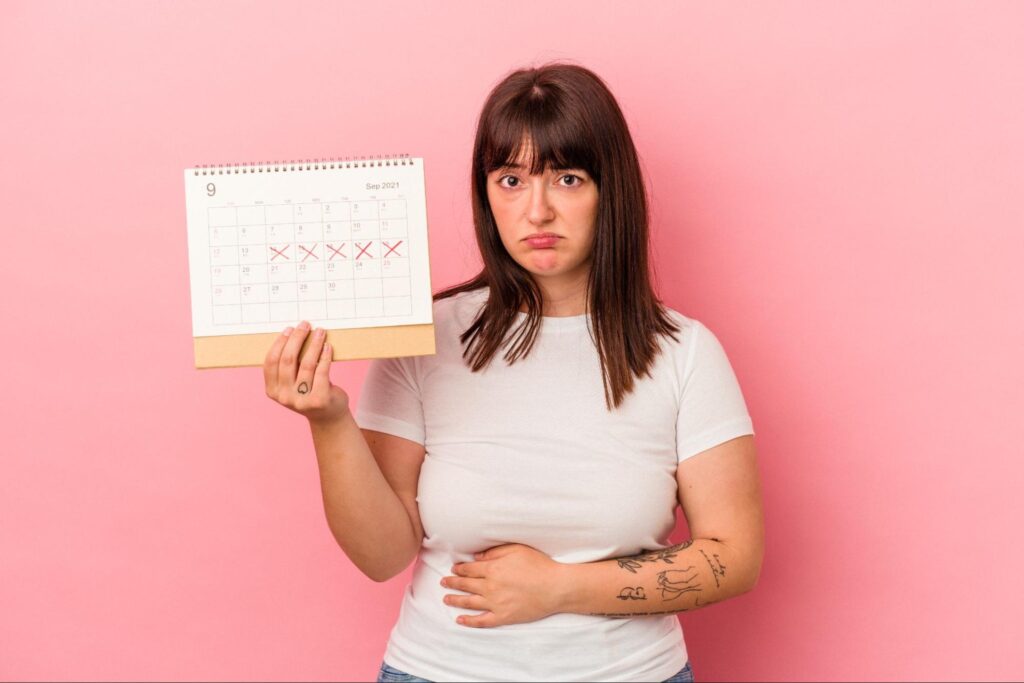 women holding a periods tracker chart suffering from pmdd symptoms
