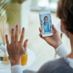 Close-up of woman greeting virtual urgent care from home suing her smartphone