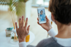Close-up of woman greeting virtual urgent care from home suing her smartphone